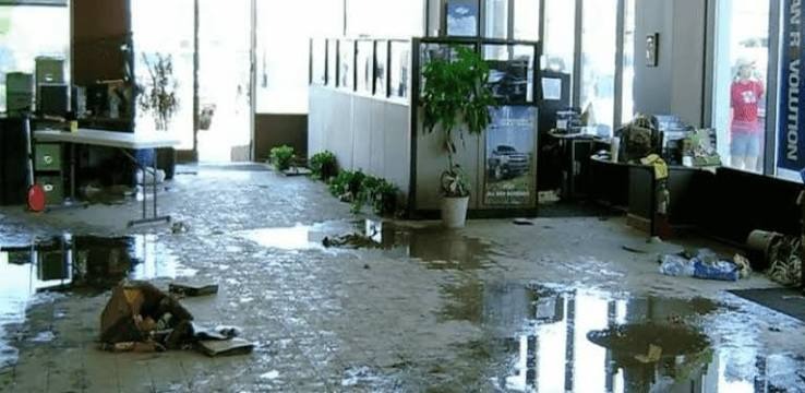 Standing floodwater and mud residue across commercial retail showroom and office workstations in Miami